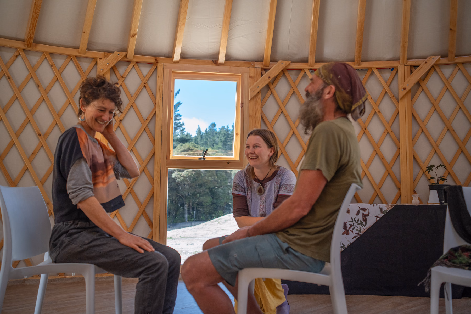 Mia Ruby Harrison laughing with people during a gathering in a wooden yurt